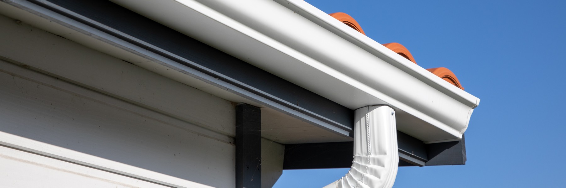 White gutter and downspout along a home eave
