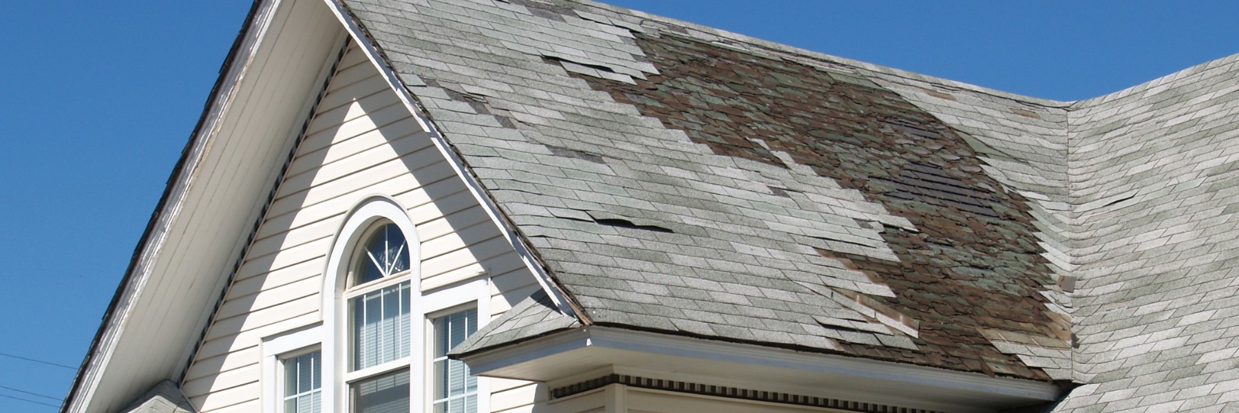 Worn asphalt shingle roof with missing and curling shingles