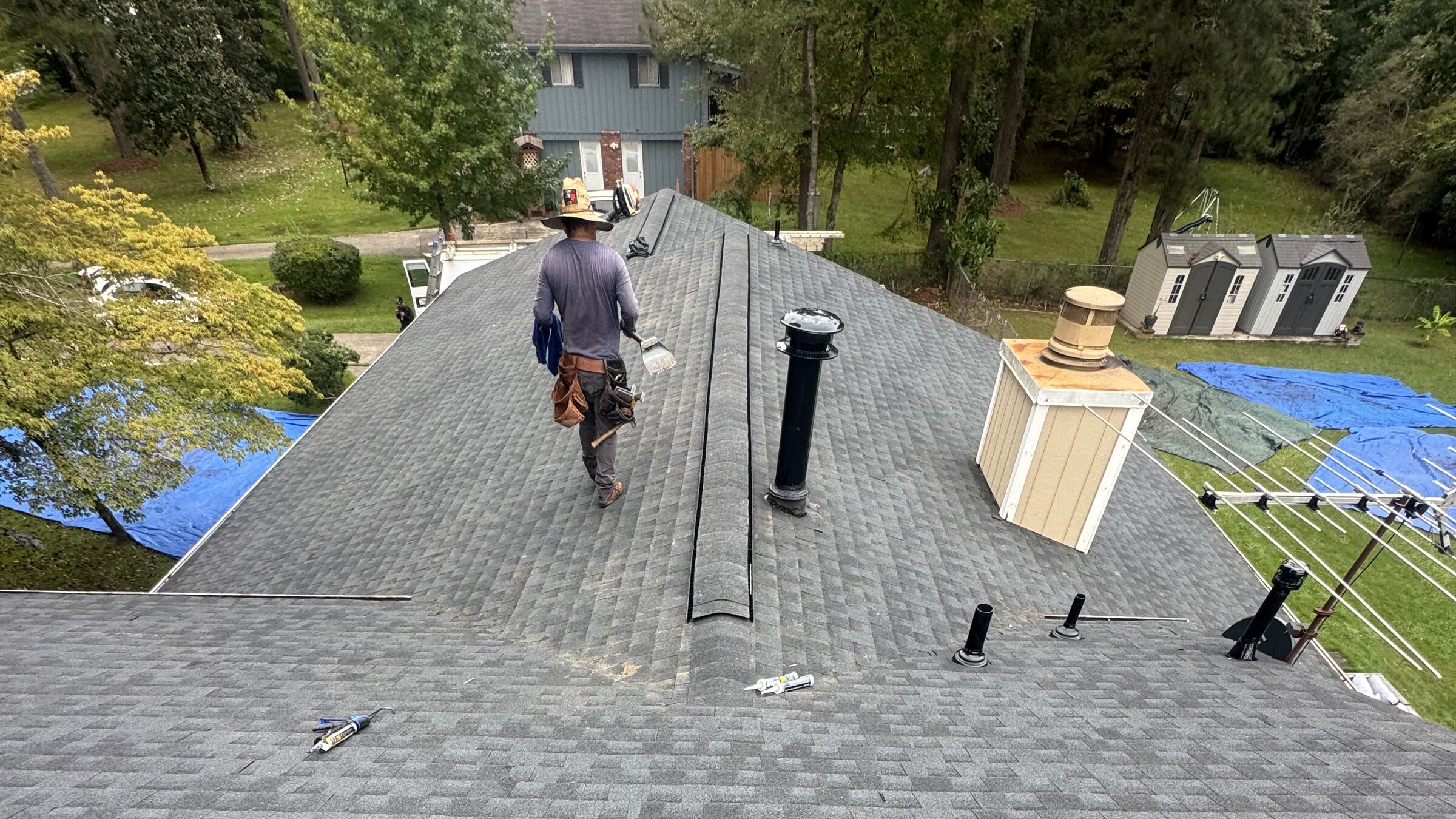 Roofer walking a newly installed gray shingle roof