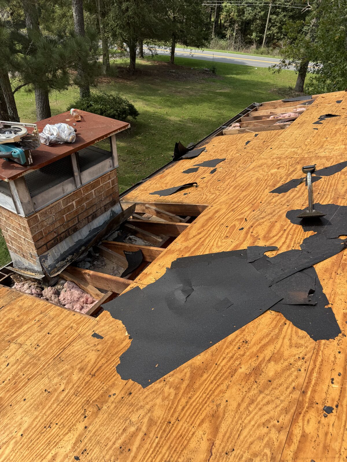 Roof tear-off with new plywood decking around a brick chimney