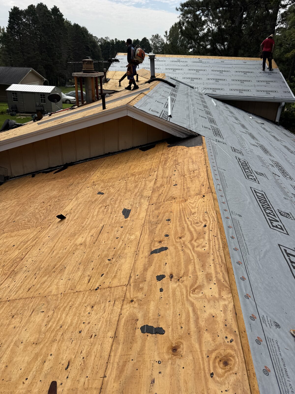 Crew installing synthetic underlayment over new roof decking